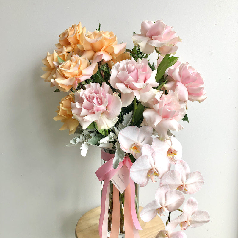 a perfect deluxe roses arrangement in a vase with phalaenopsis orchid